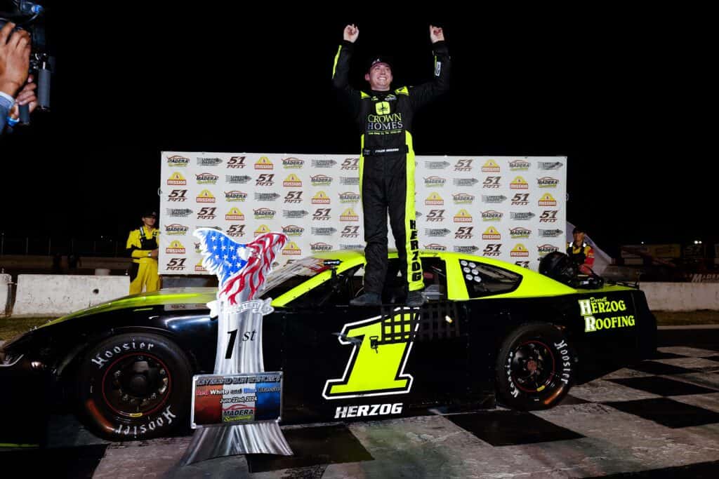 Race car driver celebrating win on the podium at Madera Speedway.