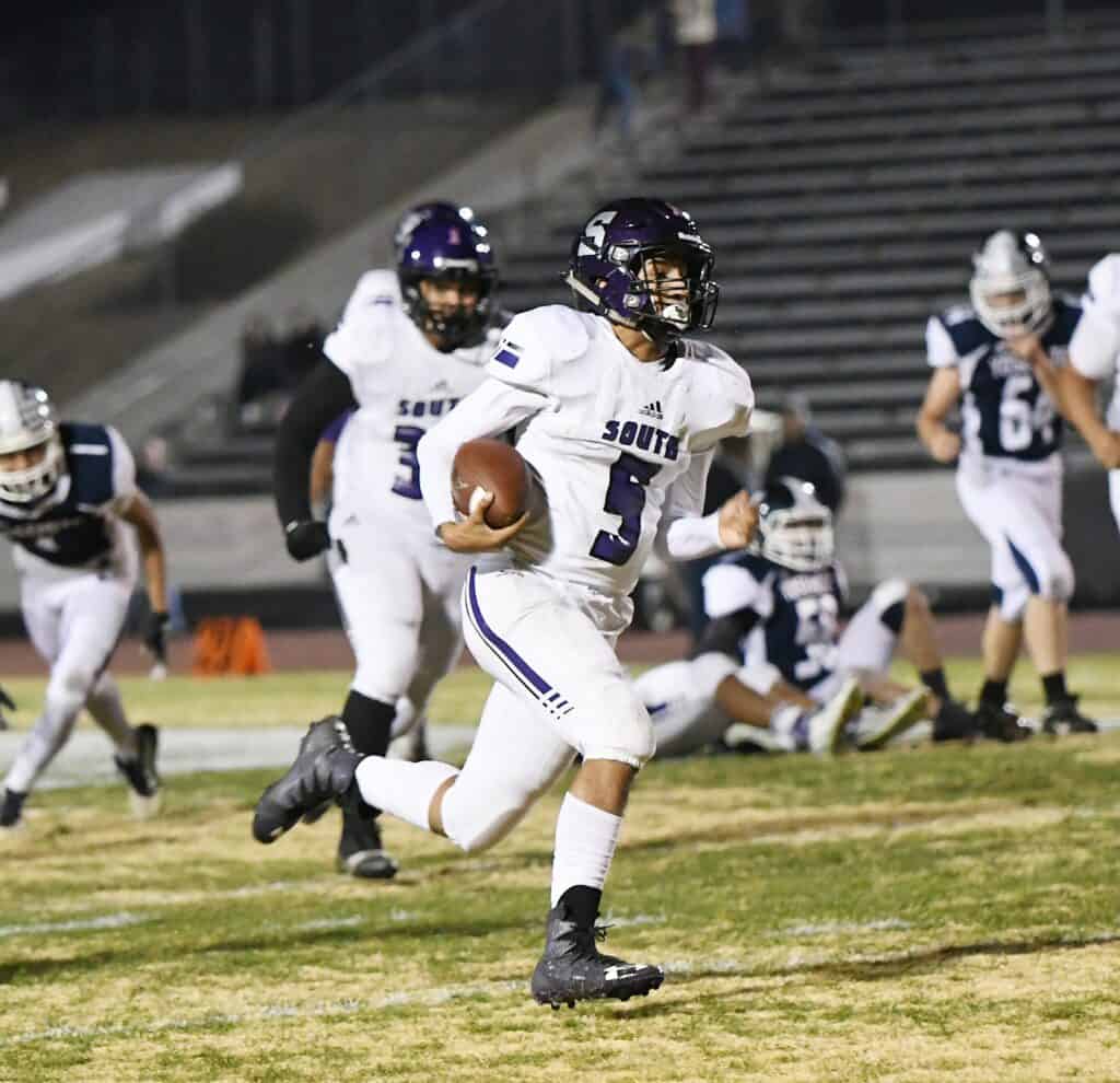 Madera football player running with ball during game.