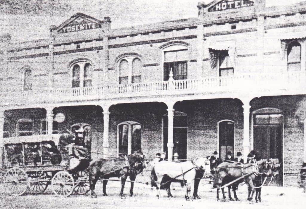 Historic Madera Hotel with horse-drawn carriages outside.