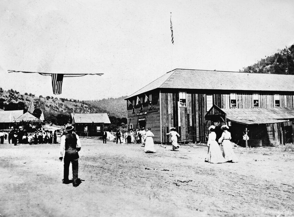 Historic black-and-white photo of early Madera County fairgrounds with people and buildings.