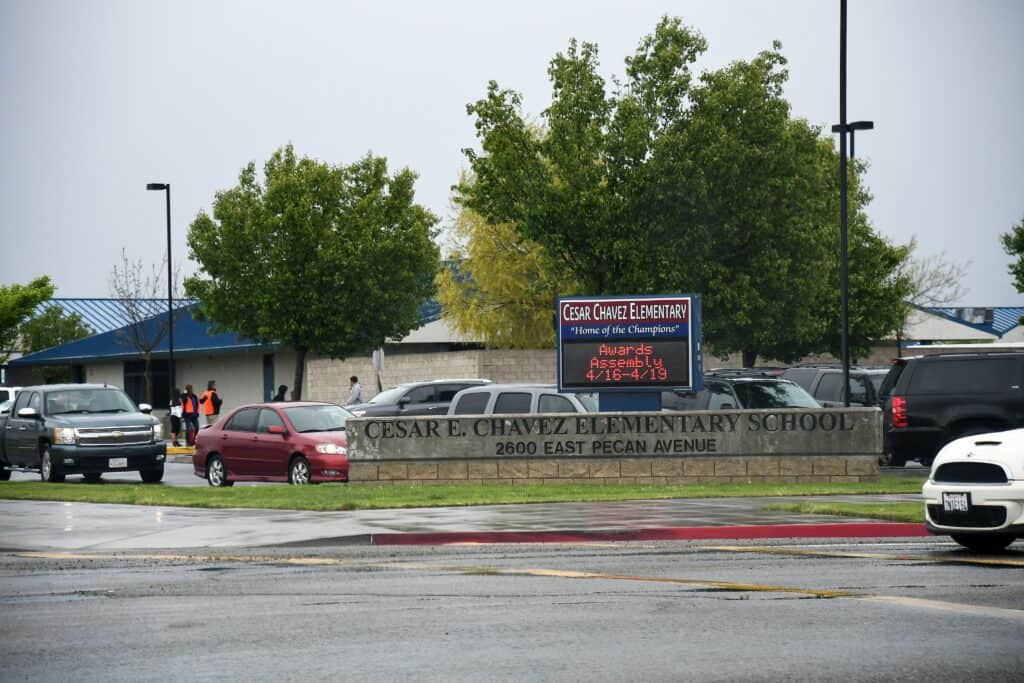 Cesar E. Chavez Elementary School entrance with parking lot and trees.