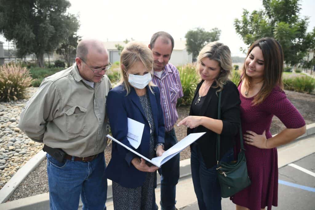 Group of professionals reviewing plans outdoors in a community setting.