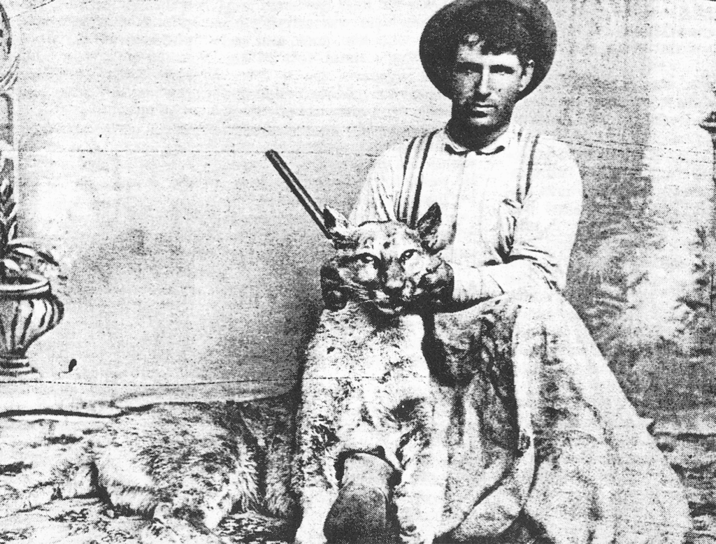 Ancient photo of a man with a large cat and a rifle.