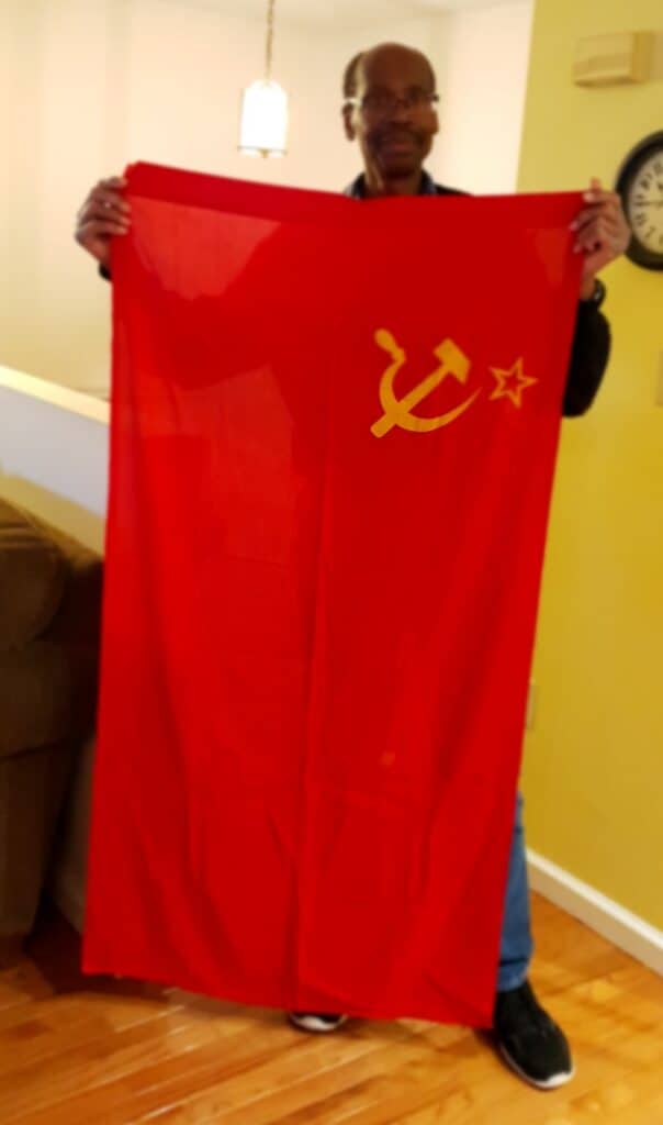 Man holding a Soviet Union flag indoors, Madera Tribune coverage.