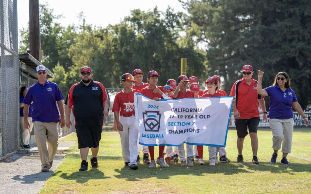 Youth baseball team holding a banner after winning California Section Championship.