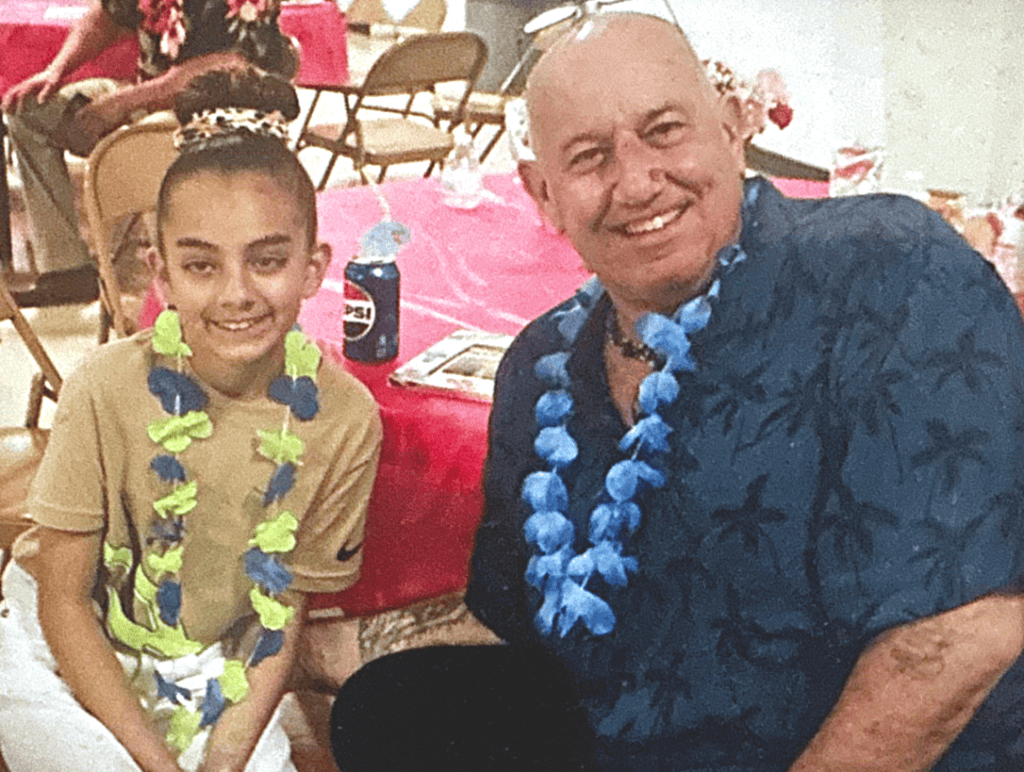 Smiling girl and man wearing leis at a community celebration in Madera.