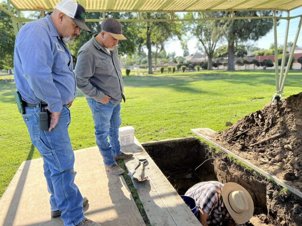 Excavation site with two men examining the historic dig in a park setting.