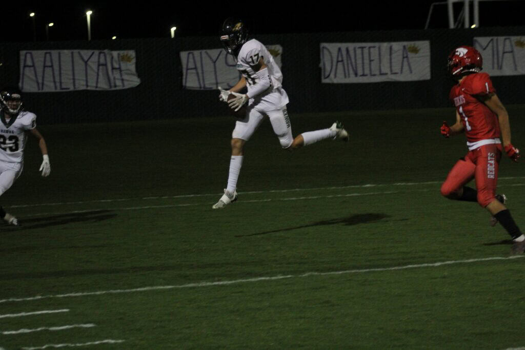 Youth football player catching the ball during a night game.
