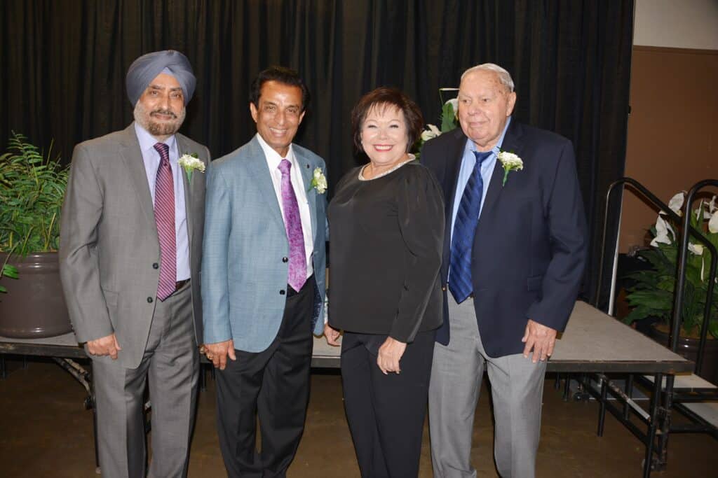 Diverse group of professionals at a formal event in front of a black curtain.