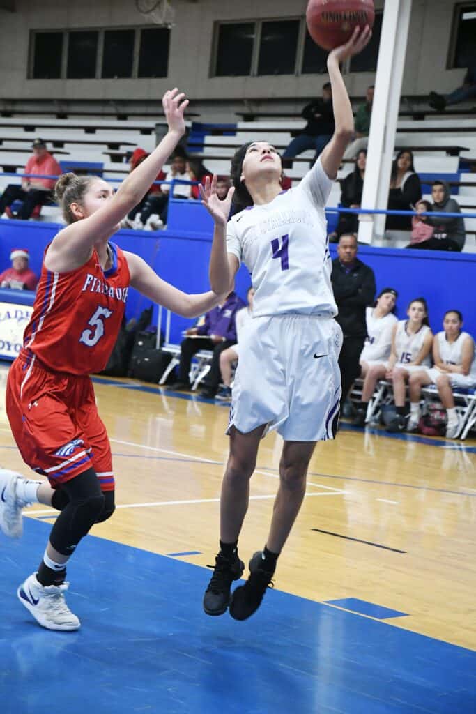 Young female basketball player shooting a layup.