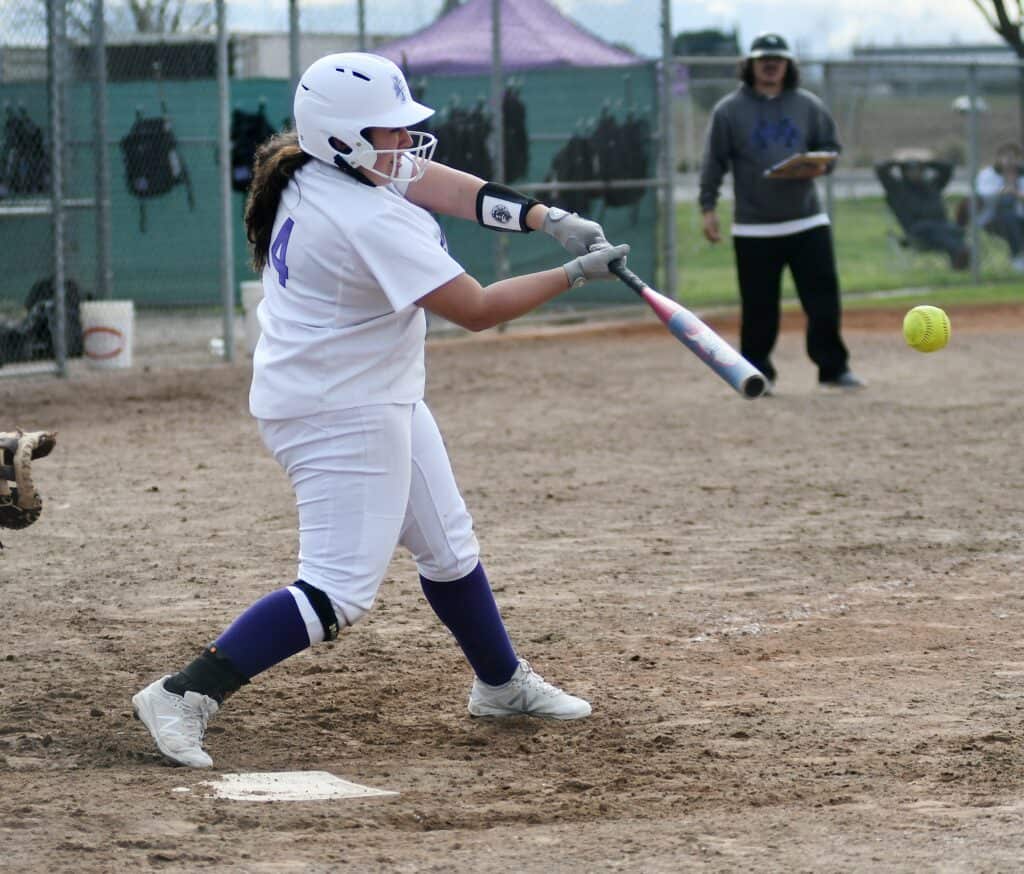 Young girl batting in a youth baseball game.
