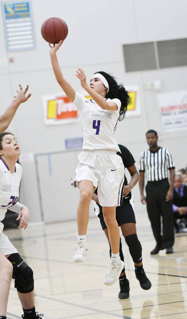 Girls' basketball player shooting during game.