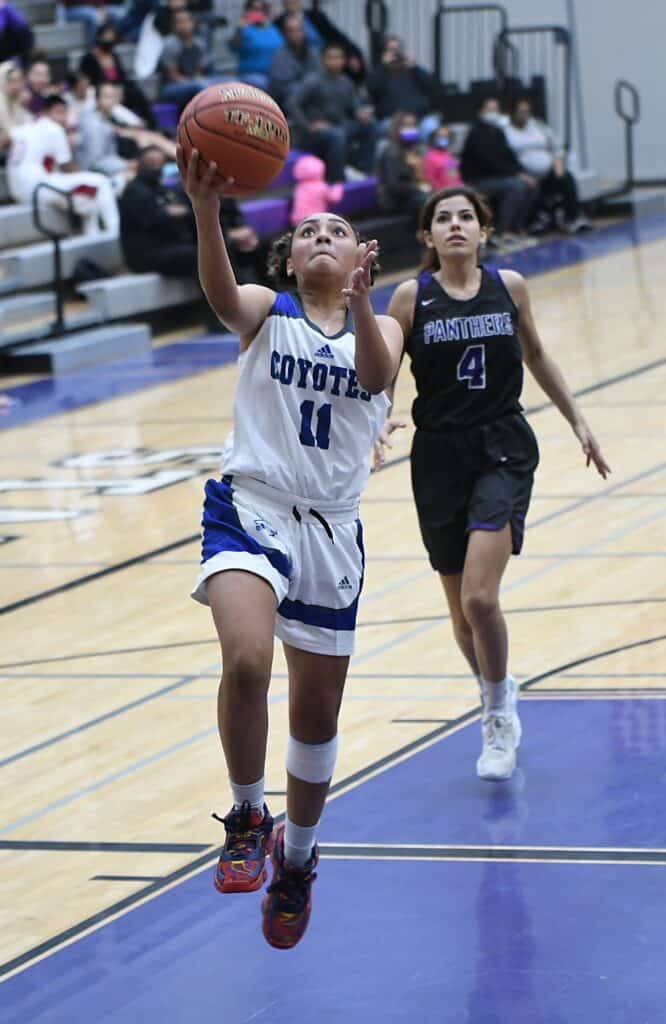 Young female basketball player shooting a layup during a game.