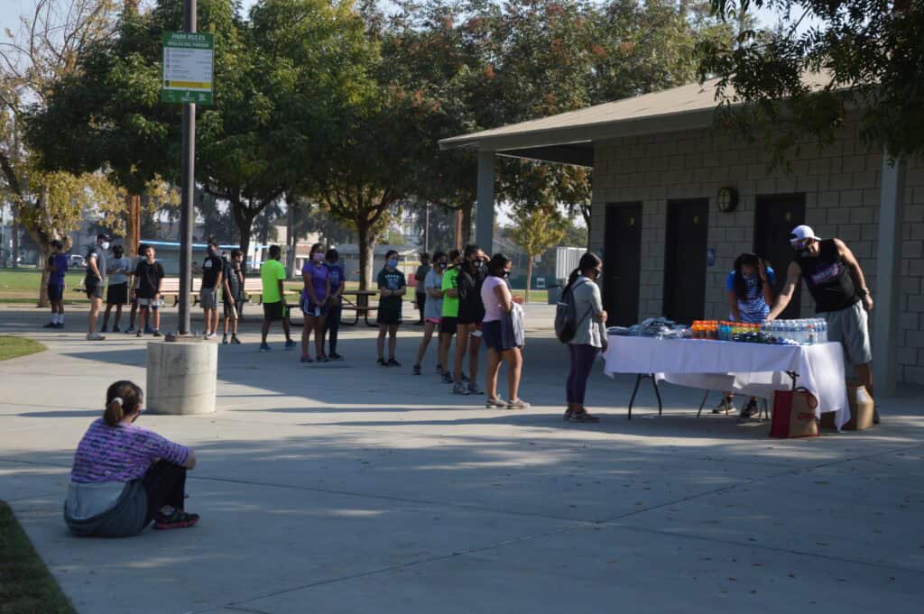 Community event at Madera school with people lining up at tables for activities.