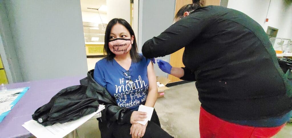 Woman receiving COVID-19 vaccine at community health event.
