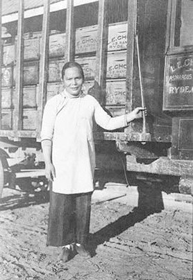 Historic photo of a young girl standing beside a train car.