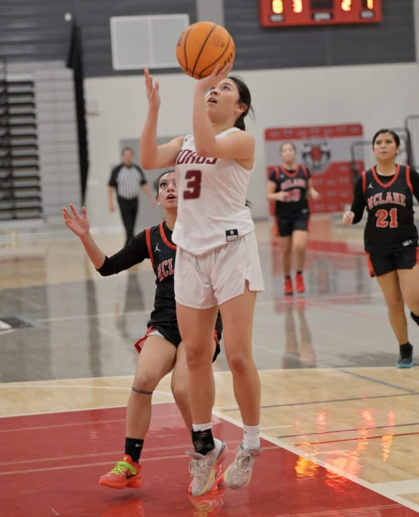 Young female basketball player shooting during game.