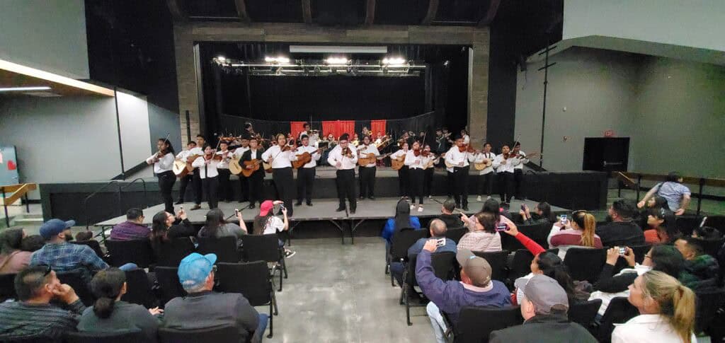 Madera school choir on stage with students singing and playing instruments.