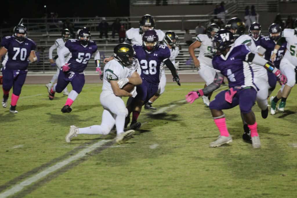 Madera football players in action during a game at night.