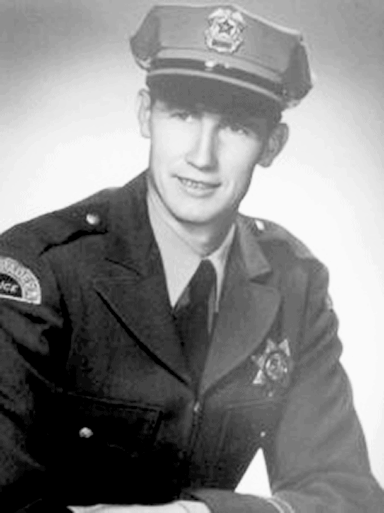 Firefighter in uniform with badge and cap, black and white image.