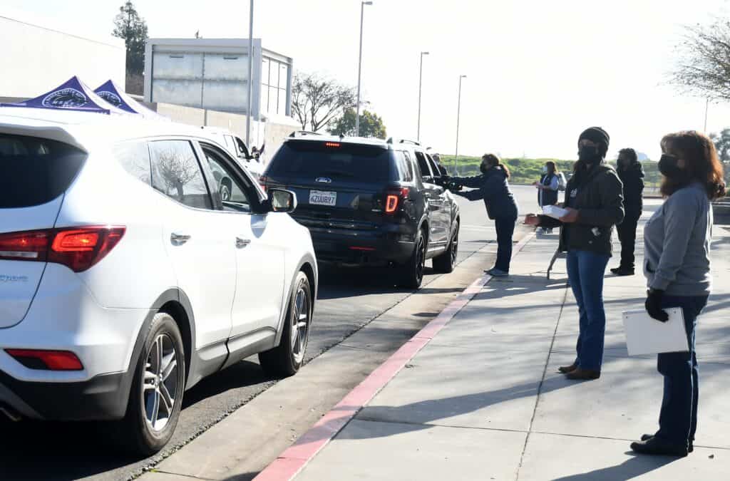 People waiting in line for car pickup at community event in Madera.