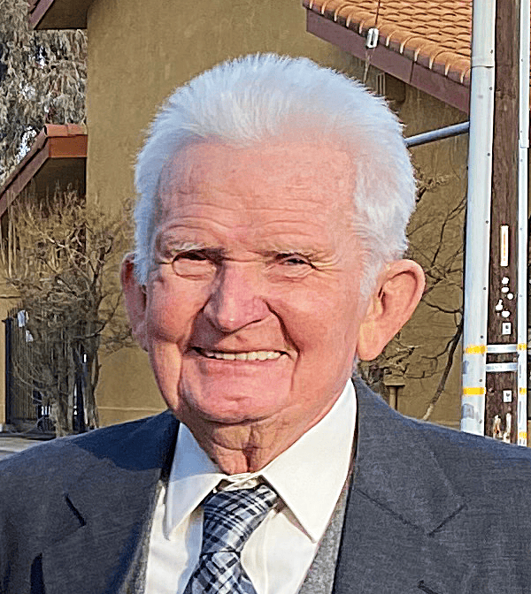 Senior man smiling outdoors in a suit and tie.