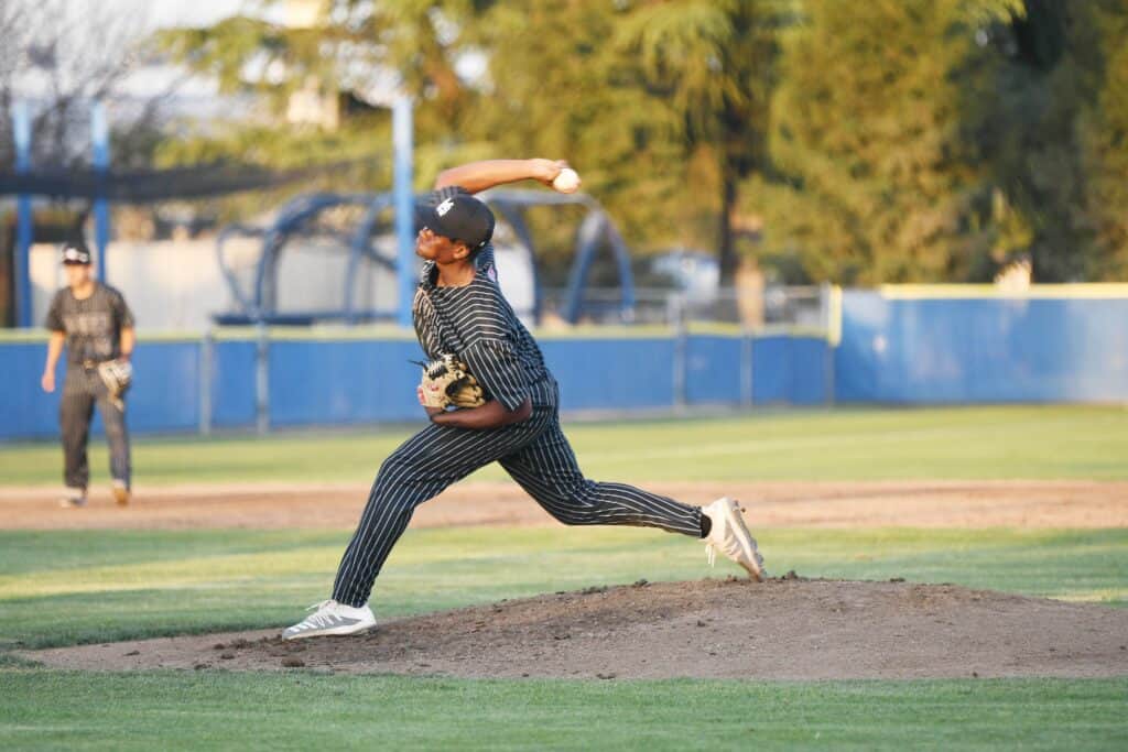 Baseball pitcher in action on the field, wearing a striped uniform and cap.