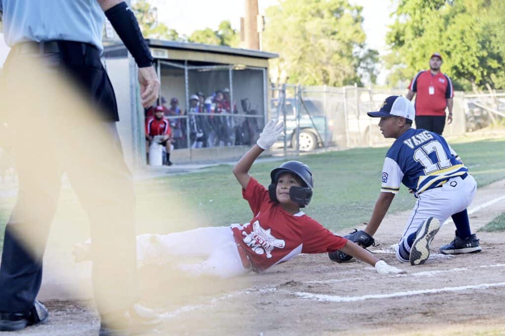 Photo - Madera American’s Rick Avila looks up for the call after hitting home plate before the tag on a passed ball. The call was safe in Monday’s 6-2 loss to Sunnyside.