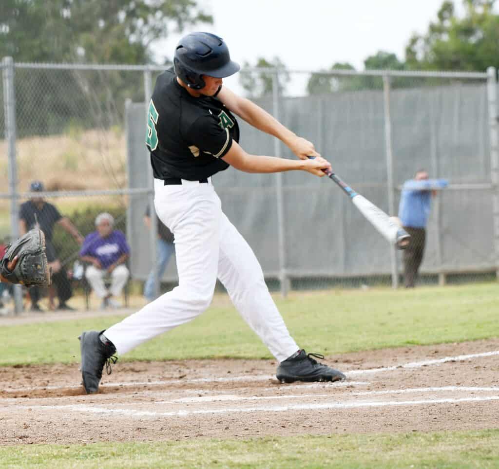 Young baseball player swinging bat during game at Madera field.