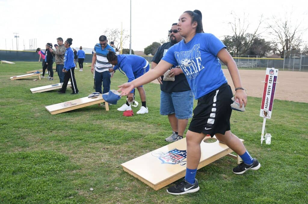 Group of people playing cornhole at community event in Madera.