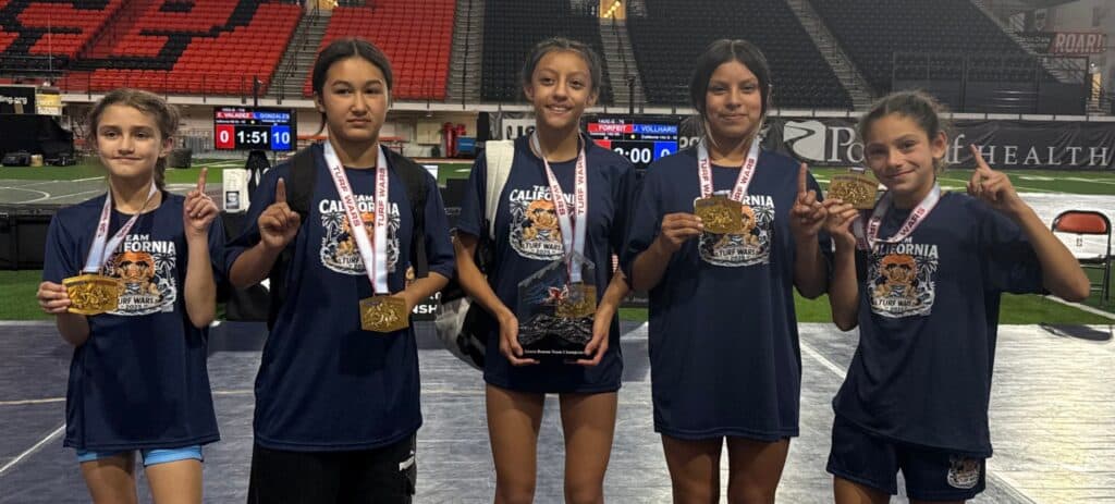 Girls' wrestling team from Madera celebrates medals at a competition.
