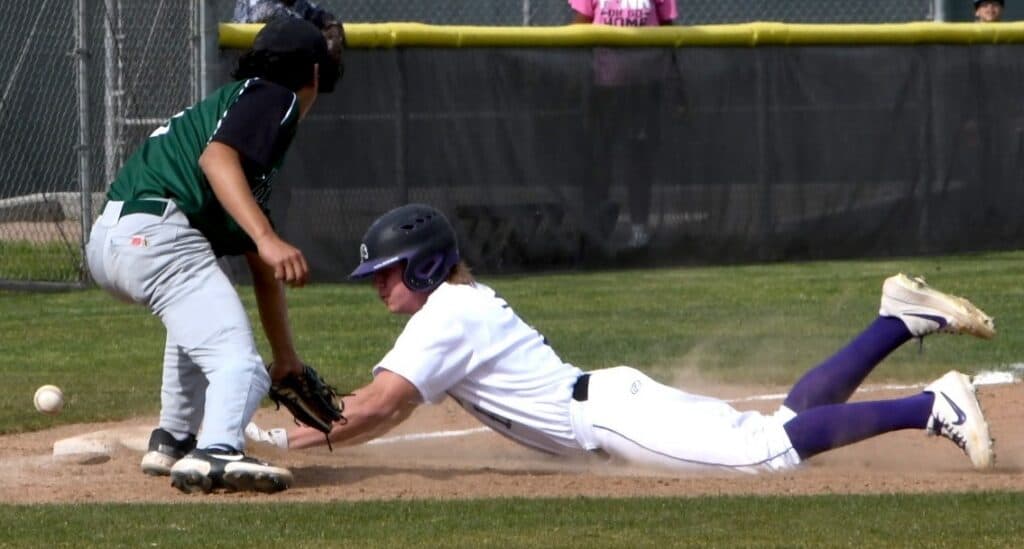Young baseball player sliding into home plate during game.