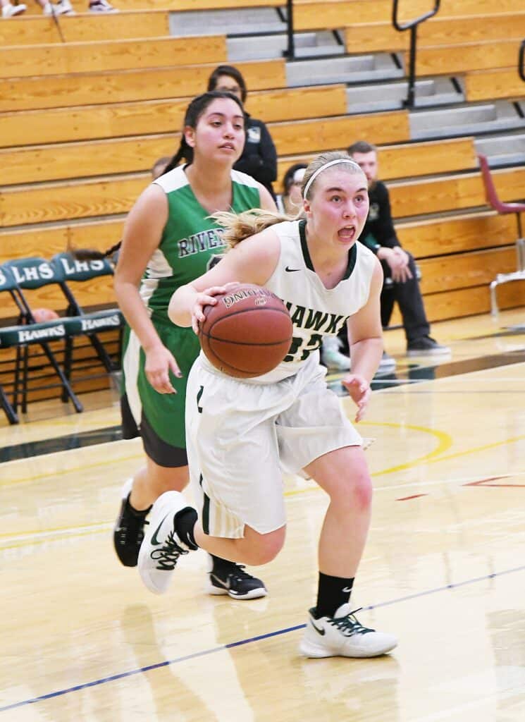 Female basketball player driving to the hoop during a game.