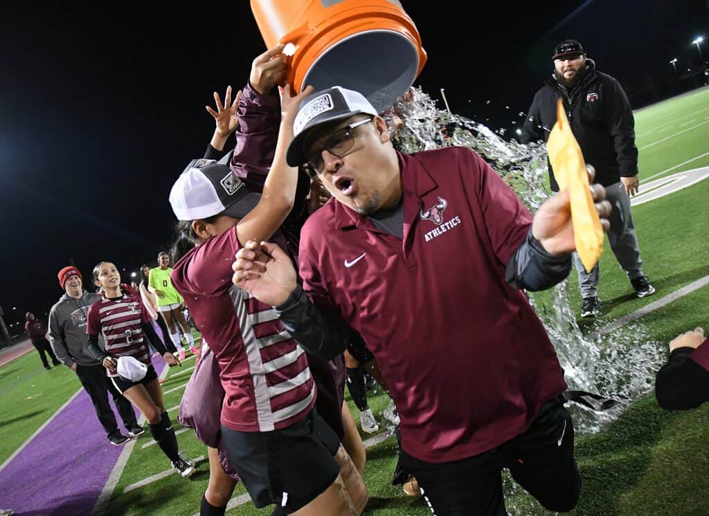 Madera High football coach douses players with water after victory.