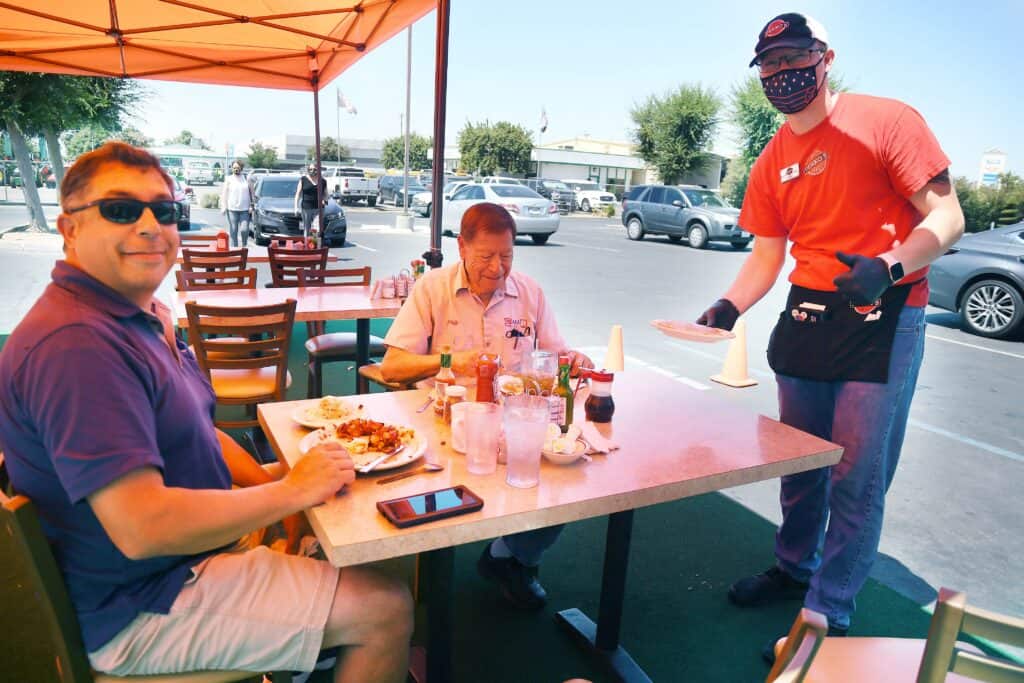 Outdoor dining at Madera restaurant with customers and staff.