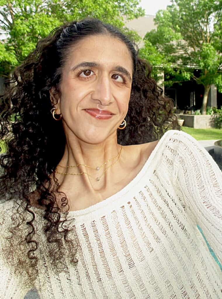 Woman with curly hair in a white sweater outdoors, Madera Tribune feature.