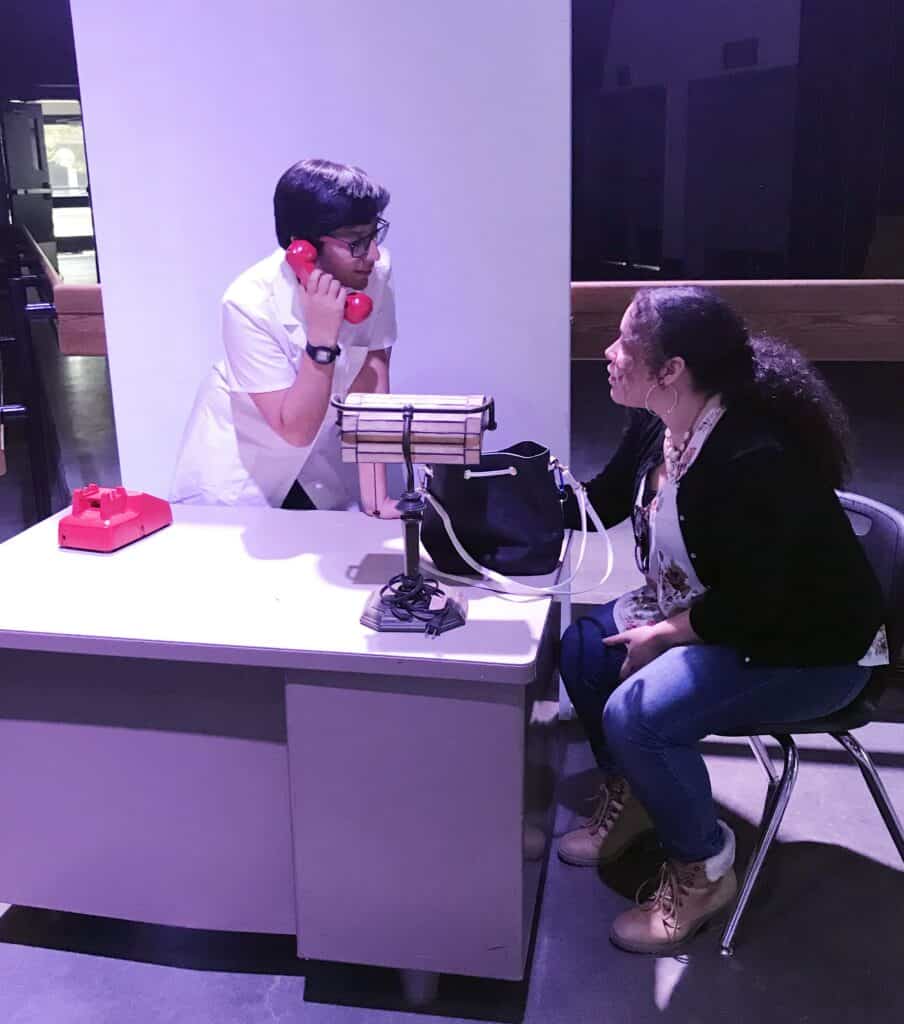 Doctor consulting with patient at clinic reception desk.