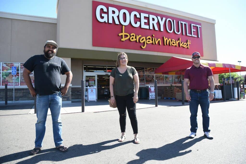 Three staff members standing outside Grocery Outlet Bargain Market store.