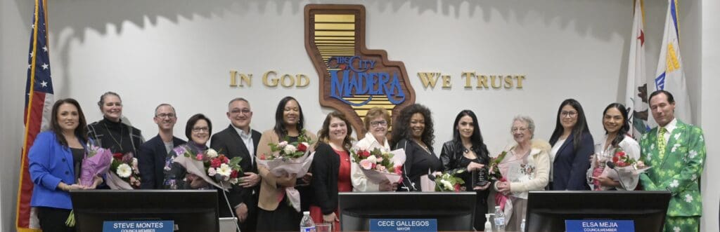 Group of women and men holding flowers at Madera Tribune event.