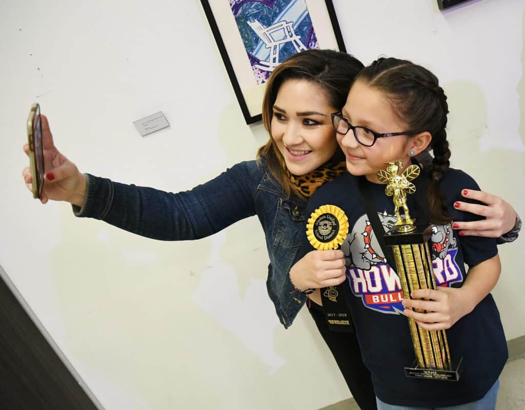Two young girls taking a selfie at award event, celebrating achievement.