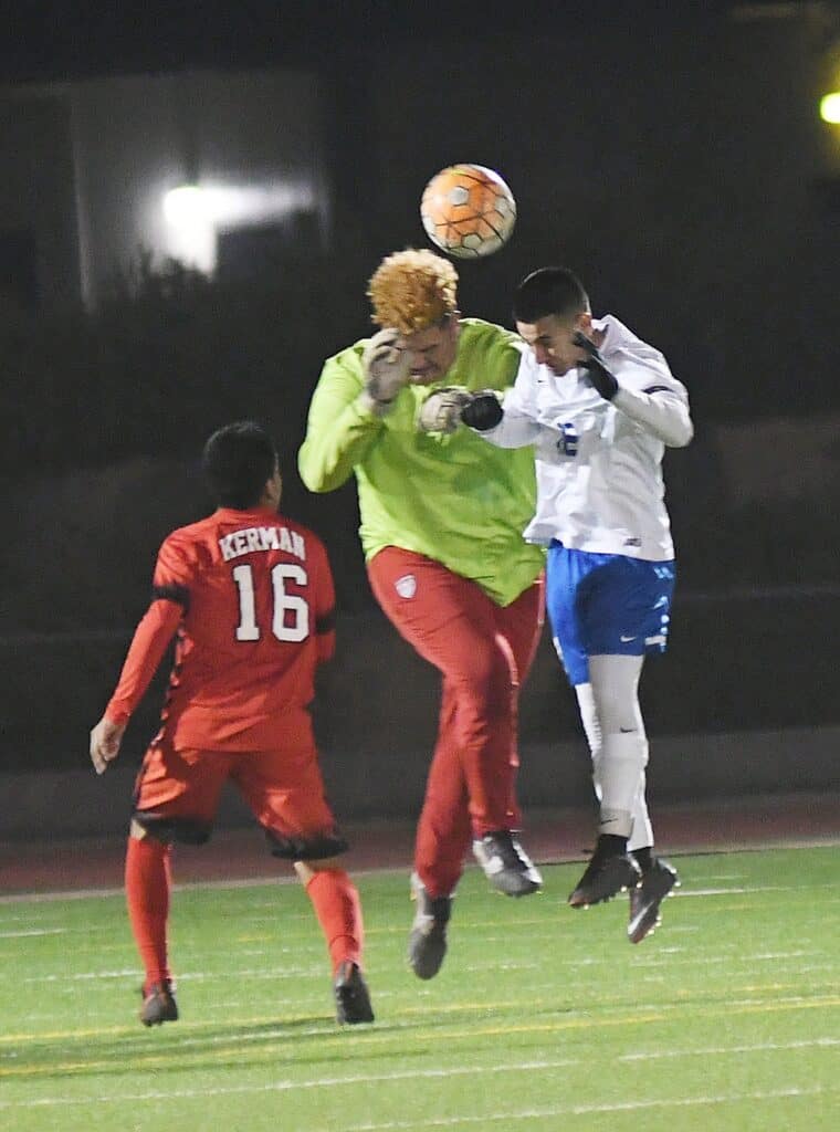 Youth soccer players competing in a match at night.