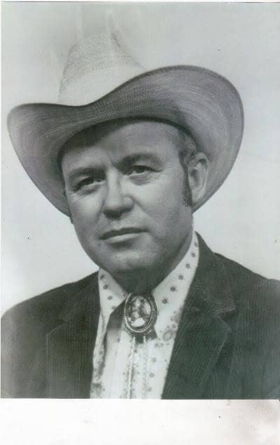 Vintage black and white portrait of a cowboy in a hat and western attire.