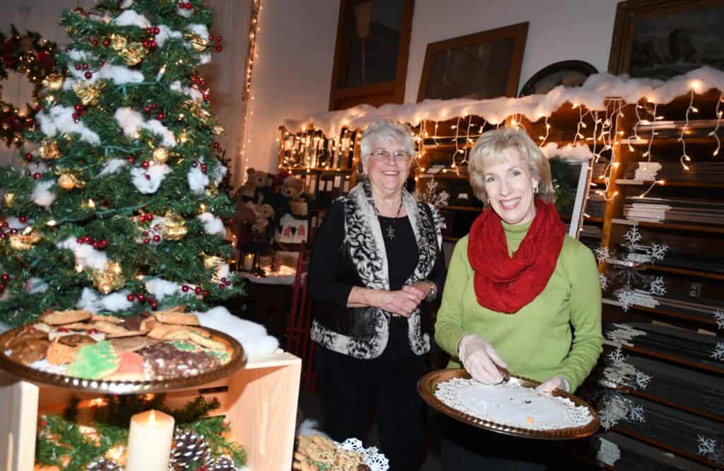 Two women baking cookies at a festive holiday gathering.