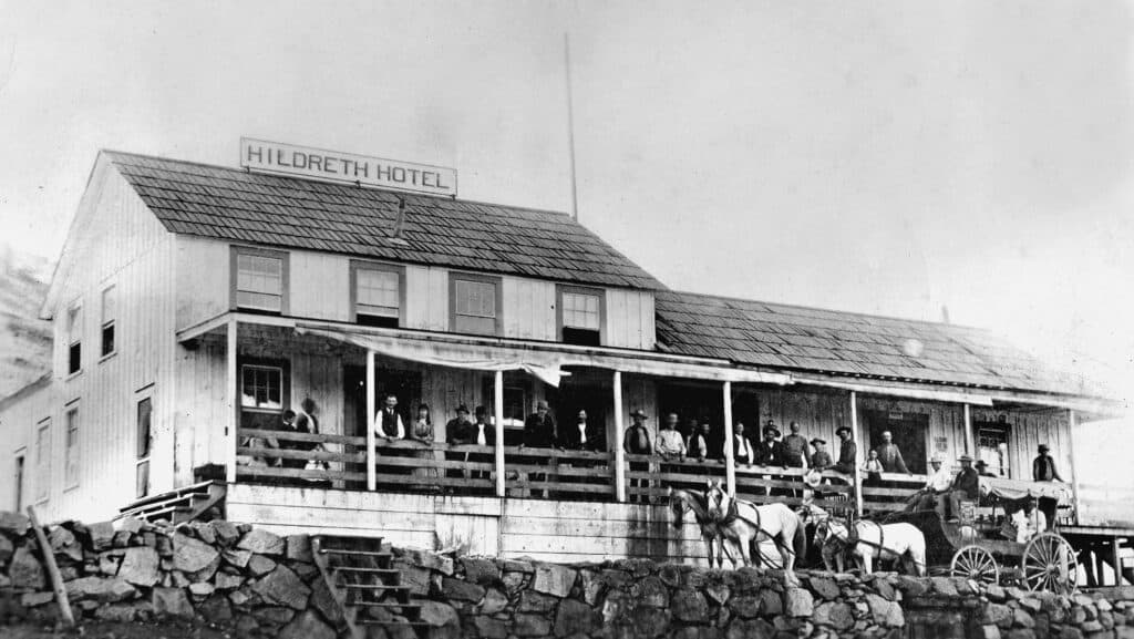 Historic Hildreth Hotel building in Madera, California, with people on the porch, early 20th century.