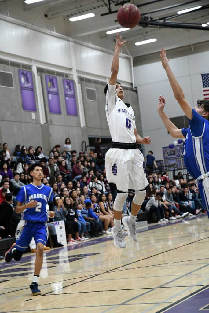 Madera High player shooting basketball during game in gymnasium.