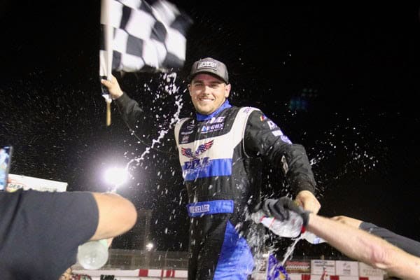 Race car driver celebrating victory at night race event.