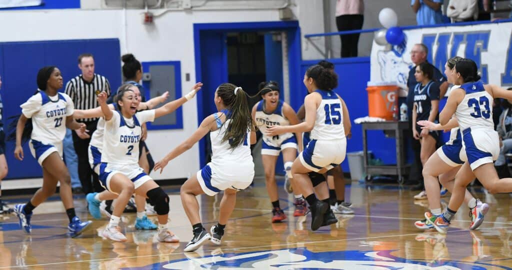 Youth girls basketball team celebrating victory on the court.