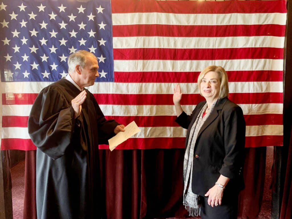 Justice swearing in new senator with American flag backdrop.