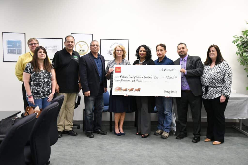 Group of people holding a large check at an award event in Madera.