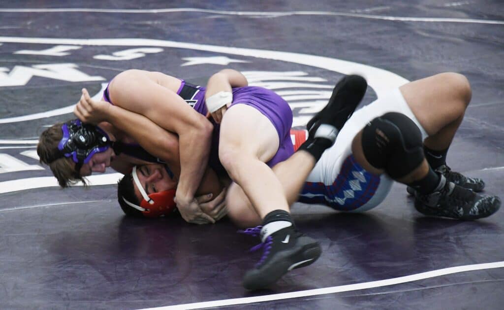 Two female wrestlers competing in a match on a wrestling mat.